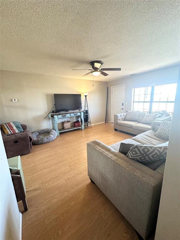 living room featuring hardwood / wood-style flooring, a textured ceiling, and ceiling fan