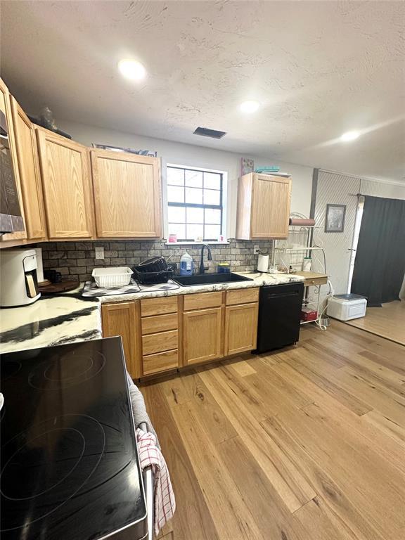 kitchen with appliances with stainless steel finishes, sink, backsplash, light hardwood / wood-style floors, and a textured ceiling