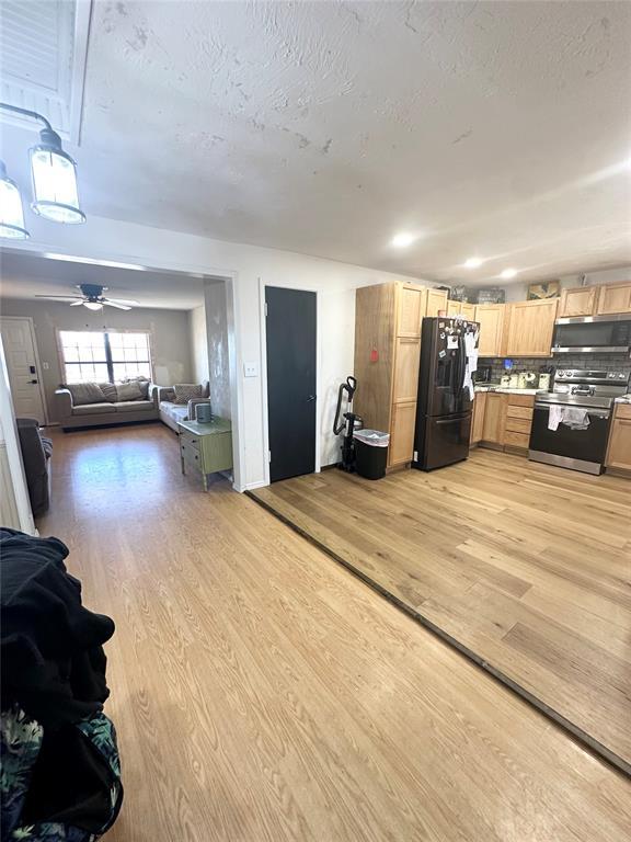 kitchen featuring light brown cabinetry, light hardwood / wood-style flooring, a textured ceiling, ceiling fan, and stainless steel appliances