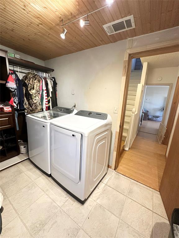 washroom featuring wood ceiling, washer and clothes dryer, and rail lighting