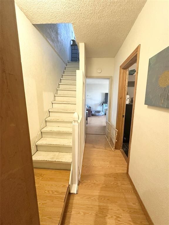 staircase featuring hardwood / wood-style flooring and a textured ceiling