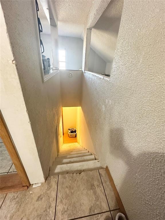 stairs with lofted ceiling and a textured ceiling