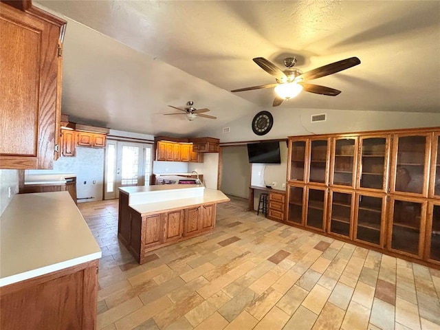 kitchen featuring sink, a kitchen island, ceiling fan, and vaulted ceiling