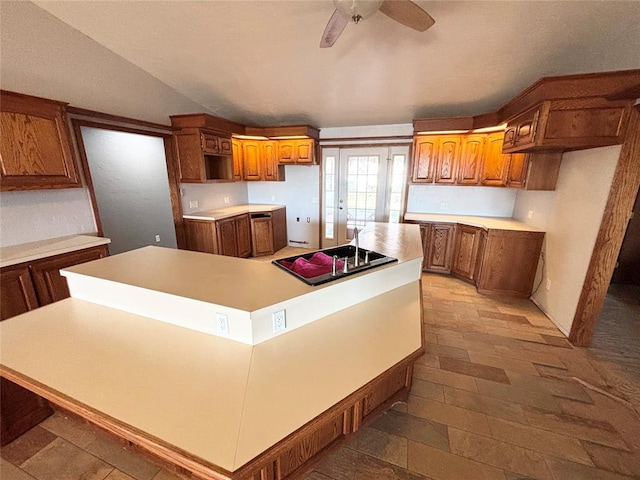 kitchen with vaulted ceiling, black stovetop, a center island, ceiling fan, and french doors