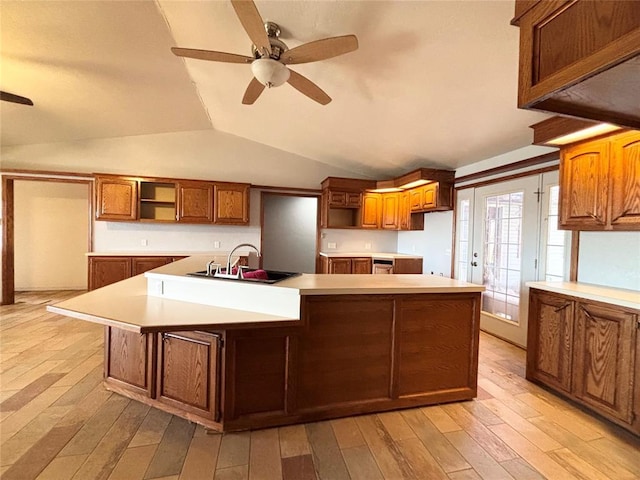 kitchen featuring sink, lofted ceiling, light wood-type flooring, ceiling fan, and a kitchen island with sink