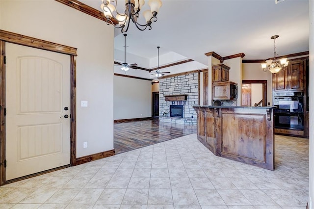 kitchen with a fireplace, a kitchen bar, ornamental molding, kitchen peninsula, and hanging light fixtures