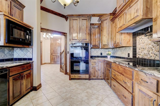 kitchen with an inviting chandelier, ornamental molding, decorative backsplash, light stone countertops, and black appliances