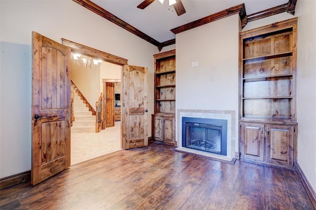 living room with built in shelves, dark wood-type flooring, ceiling fan, and crown molding