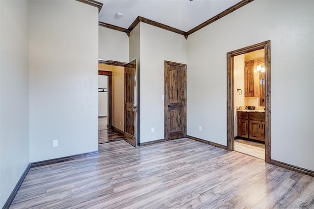 unfurnished bedroom with ensuite bath, ornamental molding, and light hardwood / wood-style floors