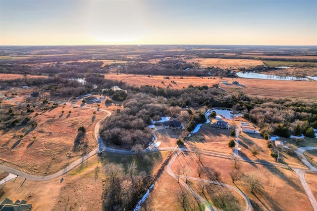 aerial view at dusk featuring a rural view and a water view