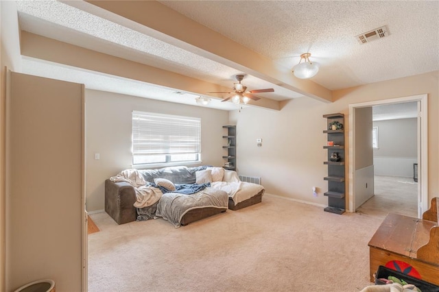 living room featuring carpet flooring, a textured ceiling, ceiling fan, and beam ceiling