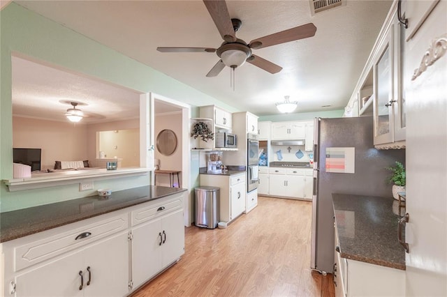 kitchen with appliances with stainless steel finishes, ceiling fan, white cabinetry, and light hardwood / wood-style floors