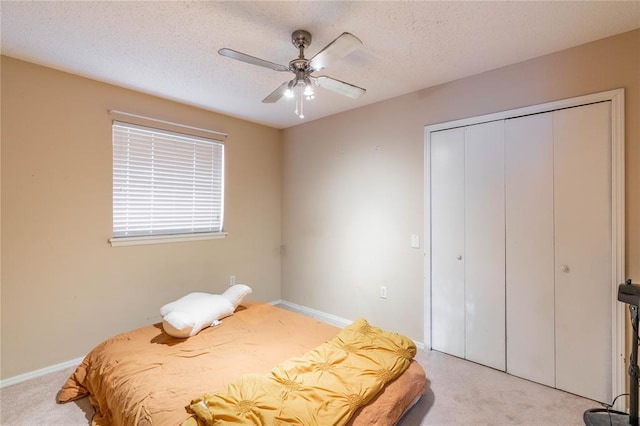 carpeted bedroom featuring ceiling fan, a closet, and a textured ceiling