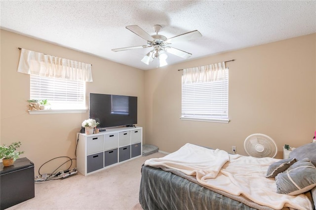 carpeted bedroom featuring ceiling fan and a textured ceiling