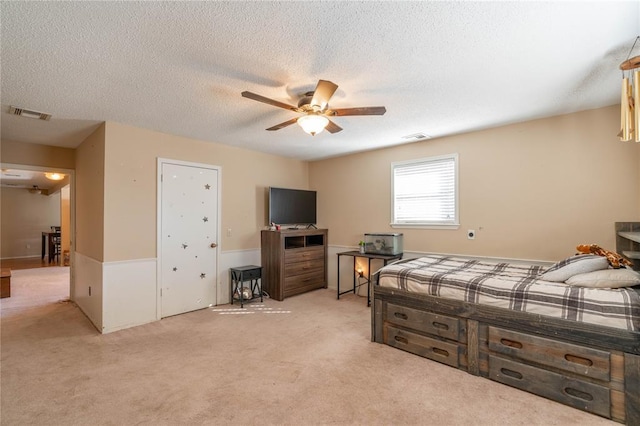 bedroom featuring a textured ceiling, ceiling fan, and light colored carpet