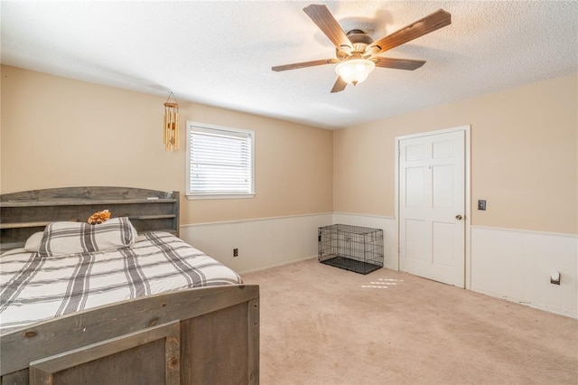 carpeted bedroom featuring ceiling fan and a textured ceiling