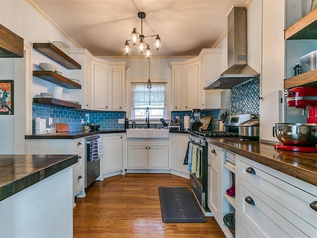 kitchen featuring stainless steel appliances, sink, white cabinets, wall chimney range hood, and pendant lighting