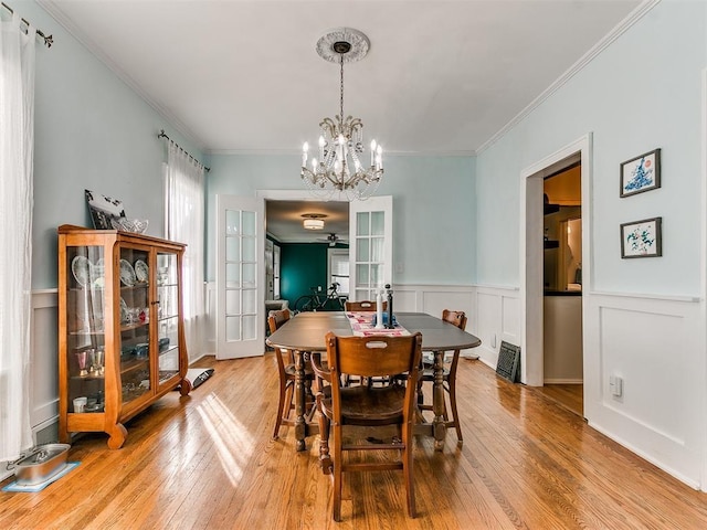 dining space featuring ornamental molding, light wood-type flooring, french doors, and a chandelier