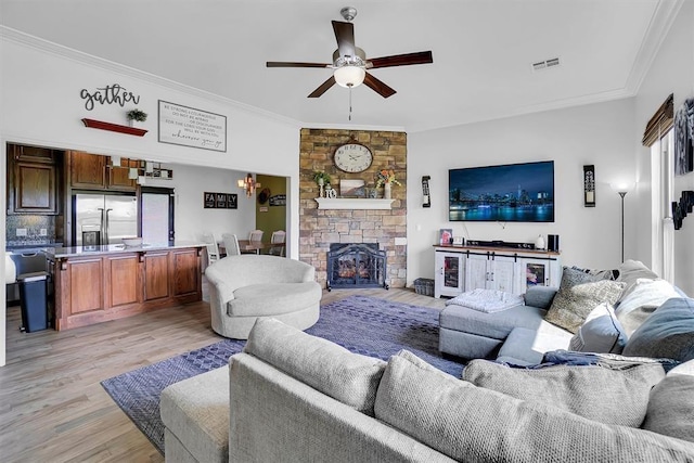 living room with ceiling fan, a fireplace, light wood-type flooring, ornamental molding, and beverage cooler