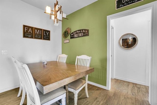 dining space with wood-type flooring and a notable chandelier