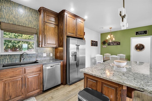 kitchen featuring sink, hanging light fixtures, a kitchen breakfast bar, stainless steel appliances, and light stone counters