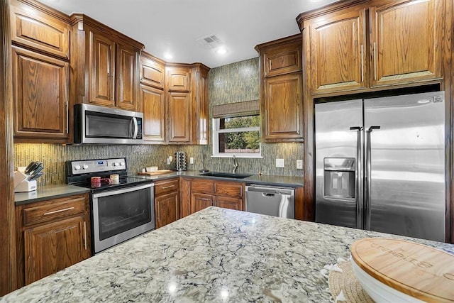 kitchen with sink, stainless steel appliances, dark stone counters, and tasteful backsplash