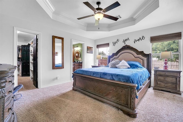 bedroom featuring ceiling fan, connected bathroom, a raised ceiling, light colored carpet, and multiple windows