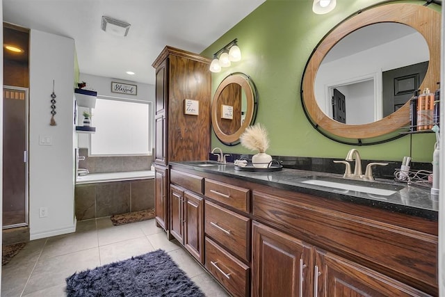 bathroom featuring tiled tub, vanity, and tile patterned flooring