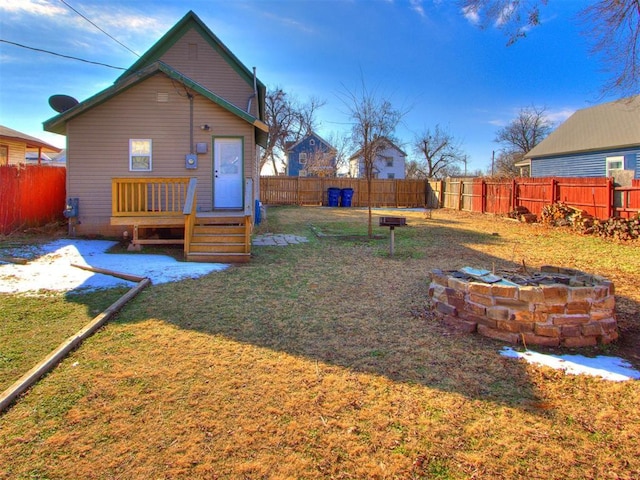 rear view of property with a yard, a deck, and an outdoor fire pit