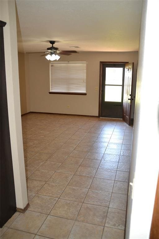 empty room with ceiling fan and light tile patterned flooring