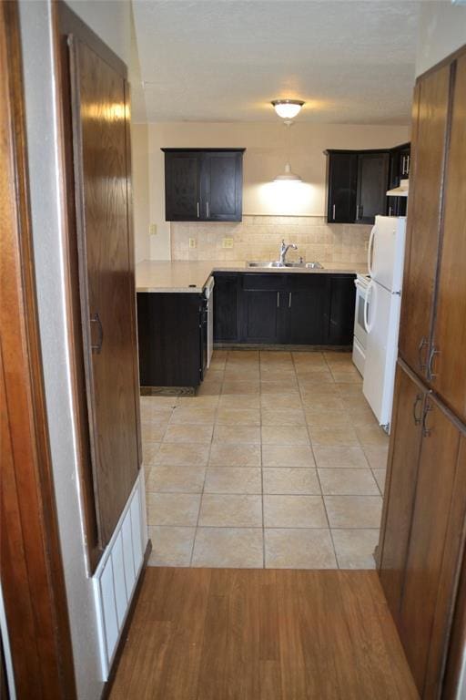 kitchen featuring white refrigerator, light tile patterned flooring, sink, and decorative backsplash