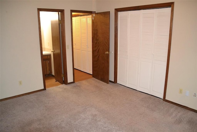 unfurnished bedroom featuring ensuite bathroom, light carpet, and a closet