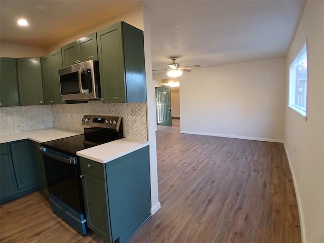 kitchen featuring green cabinets, decorative backsplash, electric range, ceiling fan, and wood-type flooring