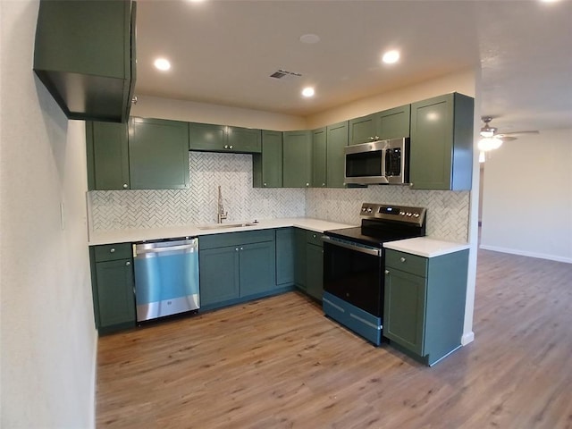 kitchen with green cabinets, appliances with stainless steel finishes, light hardwood / wood-style floors, and sink