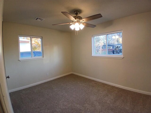 spare room with ceiling fan and dark carpet