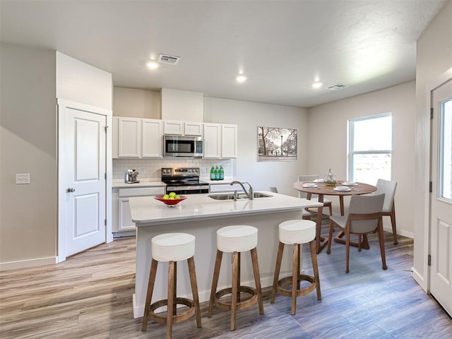 kitchen featuring an island with sink, appliances with stainless steel finishes, sink, and white cabinets