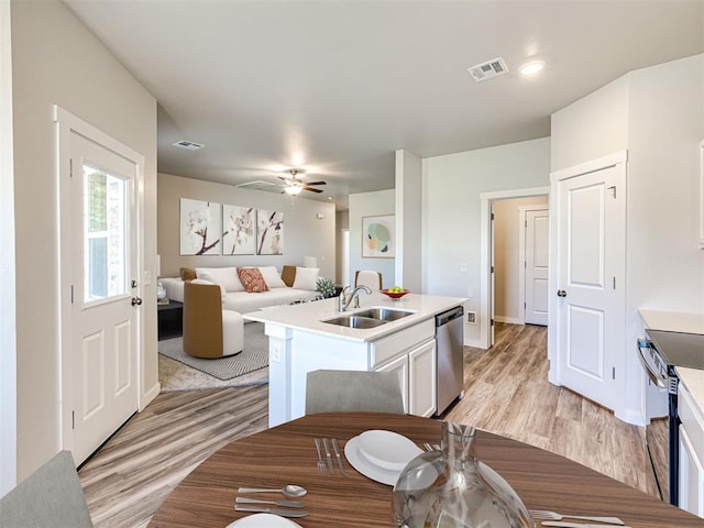 kitchen with stainless steel appliances, white cabinetry, sink, and light wood-type flooring