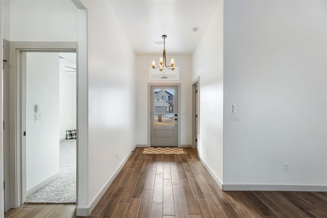 doorway to outside with dark hardwood / wood-style floors and a chandelier