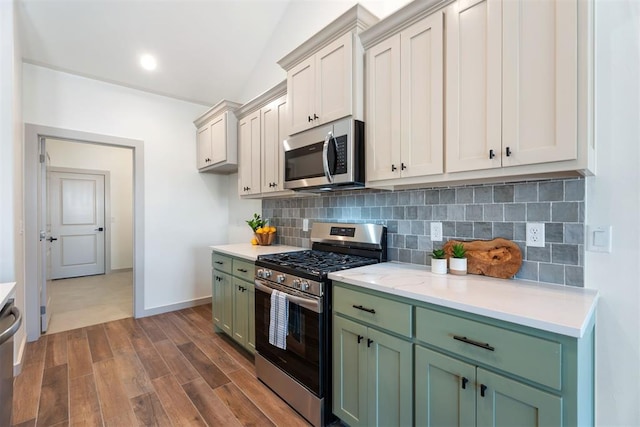 kitchen with green cabinetry, lofted ceiling, decorative backsplash, dark hardwood / wood-style flooring, and appliances with stainless steel finishes