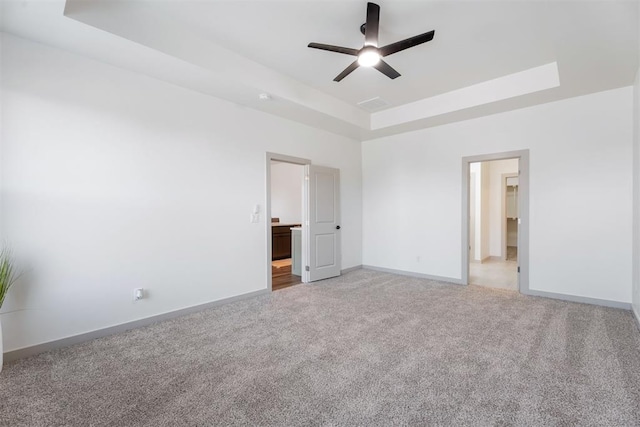 unfurnished bedroom featuring a raised ceiling, ceiling fan, and light colored carpet