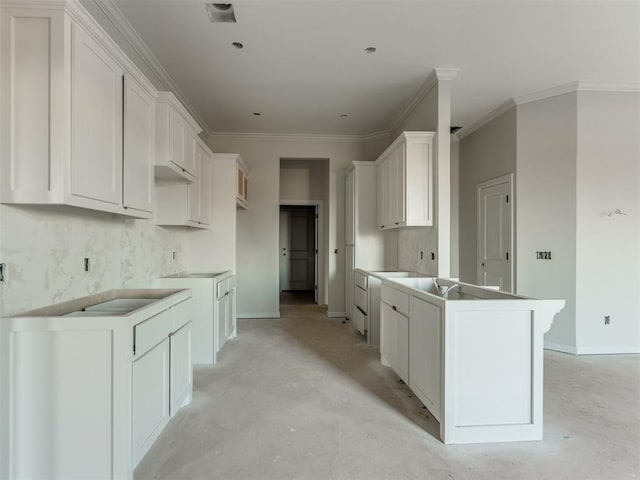 kitchen with white cabinetry, ornamental molding, and a center island