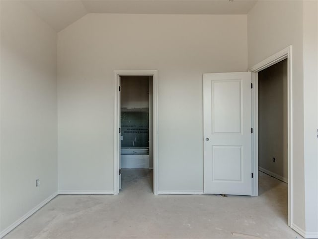 unfurnished bedroom featuring lofted ceiling and connected bathroom