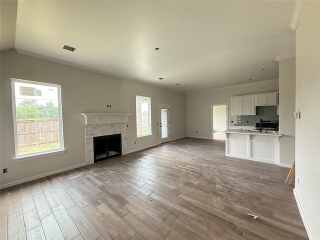 3305 NW 178th Ter, Edmond, OK 73012 - unfurnished living room with wood finished floors, baseboards, crown molding, and a fireplace