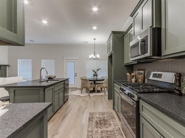 kitchen featuring sink, crown molding, light wood-type flooring, appliances with stainless steel finishes, and pendant lighting