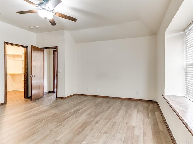 unfurnished bedroom featuring vaulted ceiling, a spacious closet, light hardwood / wood-style floors, a closet, and ceiling fan