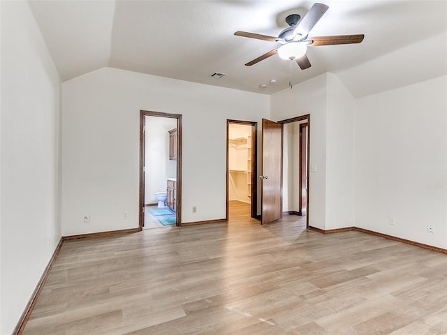 unfurnished bedroom with a spacious closet, a closet, connected bathroom, light wood-type flooring, and ceiling fan