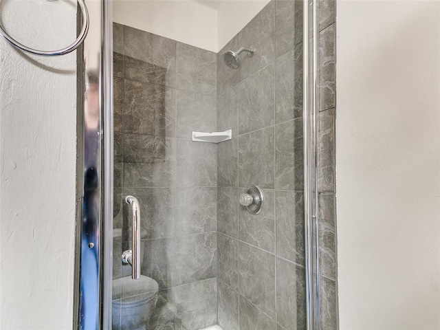 bathroom featuring a tile shower and toilet