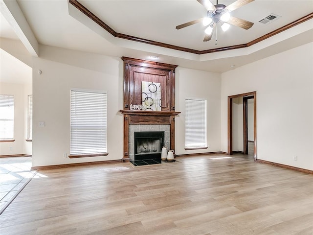 unfurnished living room with a tile fireplace, a raised ceiling, light wood-type flooring, and ornamental molding