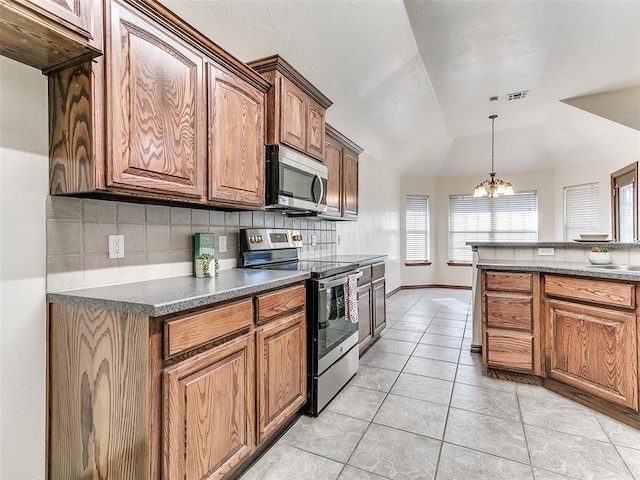 kitchen with light tile patterned floors, lofted ceiling, an inviting chandelier, backsplash, and appliances with stainless steel finishes