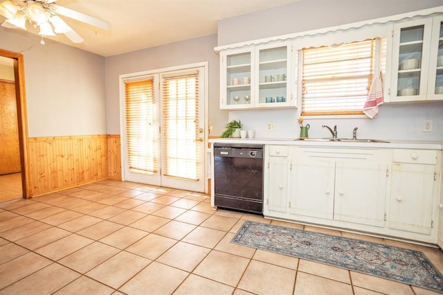 kitchen featuring dishwasher, wooden walls, light tile patterned floors, white cabinets, and sink